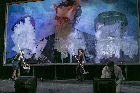 Titel: Gott ist nicht schuechtern. Nach dem Roman von Olga Grjasnowa. Regie: Laura Linnenbaum. Buehne: Daniel Roskamp. Kostueme: Michaela Kratzer. Licht: Arnaud Poumarat. Video: Jonas Englert. Dramaturgie: Sibylle Baschung. Ort: Berliner Ensemble. Urauffuehrung: 4. September 2020. Theater unter den Abstands- und Hygienebedingungen der Corona Pandemie. no model release. SpielerInnen: die beiden Hauptprotagonisten: Cynthia Micas / Amal und Armin Wahedi / Youssef uebermalen drei Portraets des Assad Clans auf einem Billboard, Oliver Kraushaar u.a..Engl: theatre, actor. adaption for the stage of a novel about the syrian civil warcopyright: david baltzer / bildbuehne.de